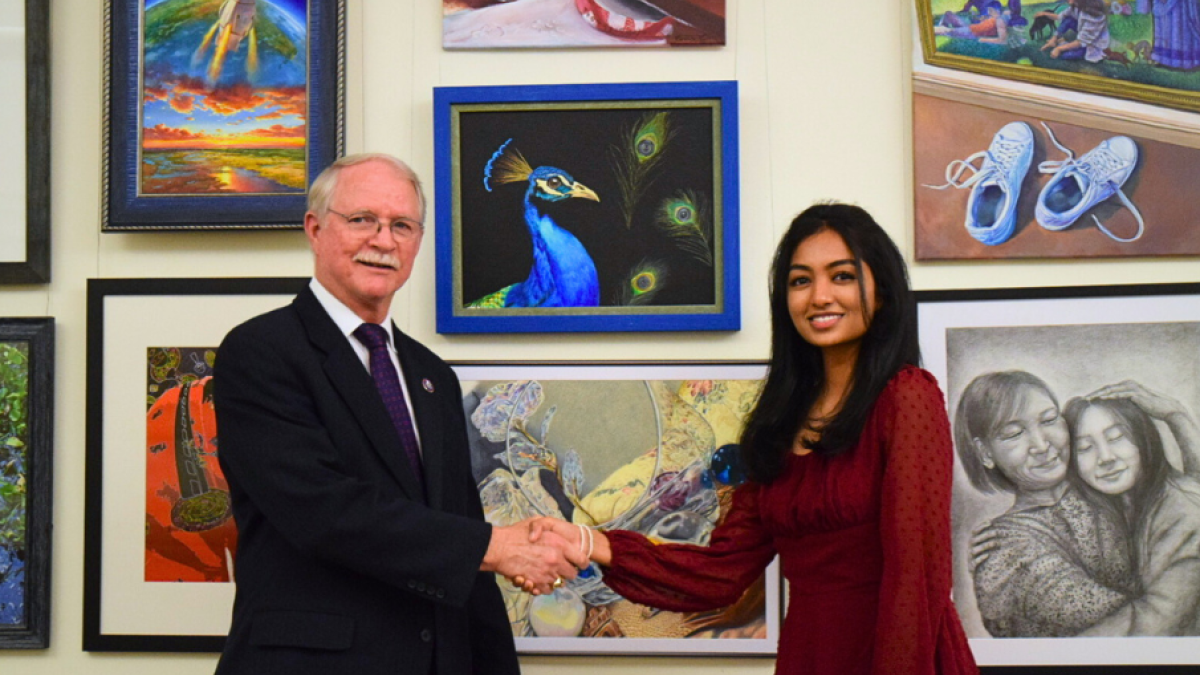 Congressman Rutherford is pictured with First Place Winner, Ashvatha Arun, alongside her winning artwork, "Eye of the Era."